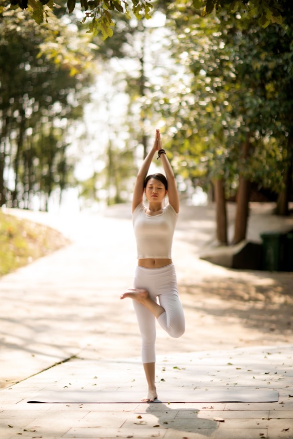 Pratiquante en posture de yoga dans un parc, lumière naturelle