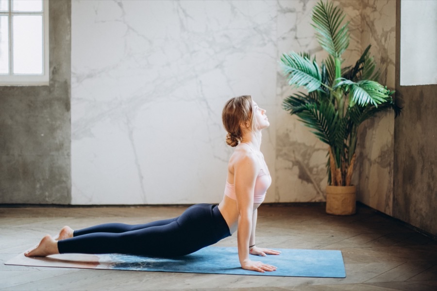 Pratiquante en posture de yoga au sol, intérieur épuré